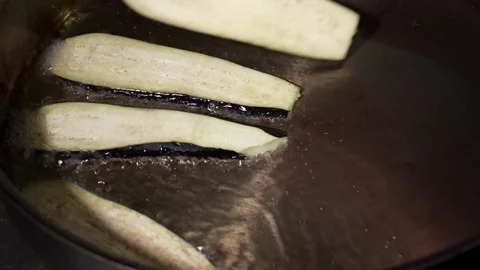 Cook putting sliced eggplant on pan for frying in the light oil Stock Footage