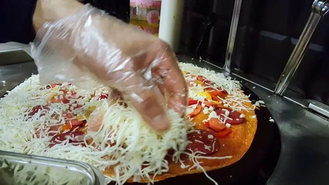 Cook putting some cheese on crepe on a black cooker Stock Footage 103885136