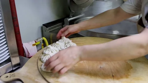 Cook quickly puts khinkali into boiling water at commercial kitchen Stock Footage 218356814