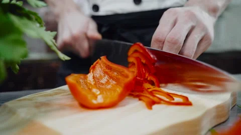 The cook quickly slices fresh red bell peppers. Video stock 146280691