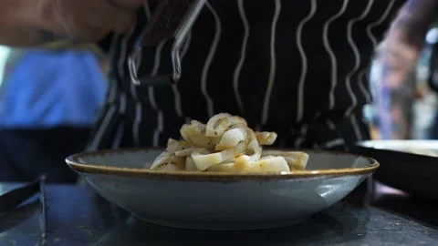 Cook in restaurant kitchen, in the bustle of decorating, rubbing salt into dish Stock Footage 141171258