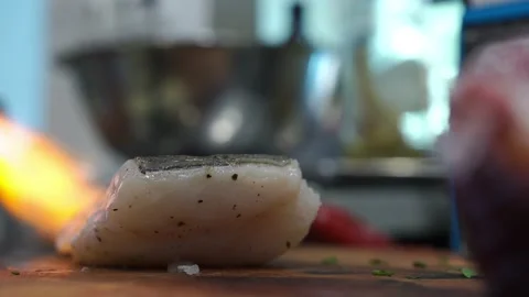 A cook in a restaurant kitchen uses a gas burner to fry cod, fish Stock Footage 140990363