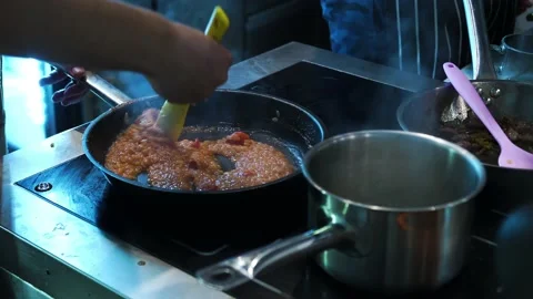 A cook in a restaurant kitchen uses a spatula to stir a dish in a frying pan. Stock-Footage 141414099
