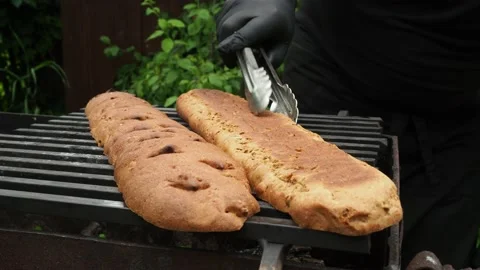 The cook roasts the baguette over the fire for a sandwich. 4K. Stock Footage 134904620