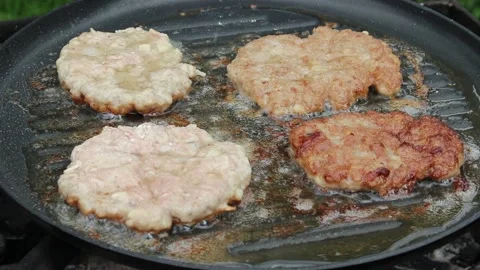 The cook roasts cutlets in a frying pan over an open fire. Stock Footage 134067755