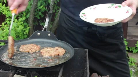 The cook roasts cutlets in a frying pan over an open fire. Stock Footage 134070398