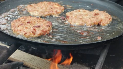 The cook roasts cutlets in a frying pan over an open fire. Stock Footage 134070404