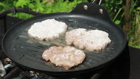 The cook roasts cutlets in a frying pan over an open fire. Stock Footage 134179004