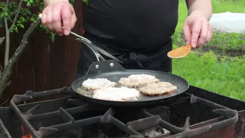 The cook roasts cutlets in a frying pan over an open fire. Stock Footage 134181731