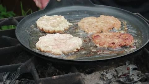 The cook roasts cutlets in a frying pan over an open fire. Stock Footage 134181768