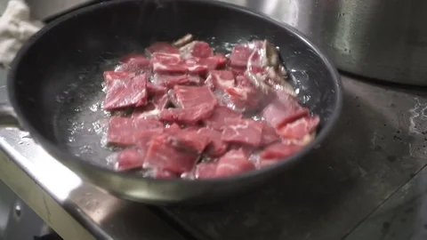 Cook roasts meat in frying pan on professional kitchen in restaurant Stock Footage 71523734