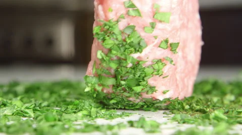 Cook is rolling a beefsteak on a parsley on a table Vídeo Stock 63068972