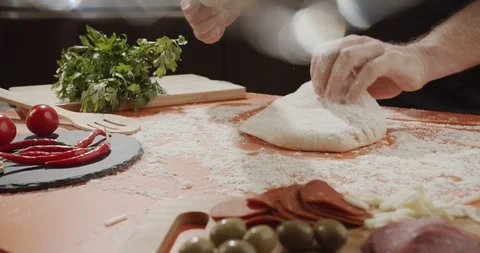 Cook rolling dough on kitchen table with wooden rolling pin for cooking pizza Stock Footage 123995057