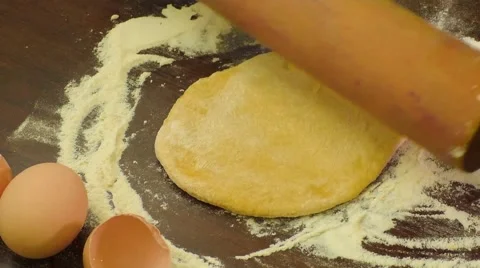 A cook is rolling dough with a rolling pin on a table Stock Footage 68373629