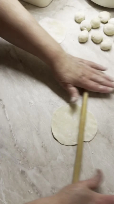 Cook rolling out dough circles with a thin wooden pin on a marble kitchen c.. Stock Footage 337669772