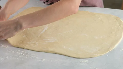 Cook rolls the dough with a rolling pin, shaping the dough. Female hands Stock Footage 146501703