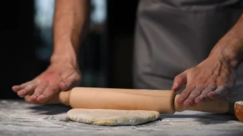 The cook rolls out the dough with a rolling pin Stock Footage 175933606