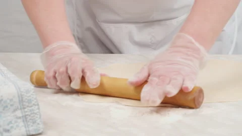 Cook rolls out thin dough with a wooden dough roller with flour. 库存影片 149166774