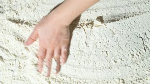 Cook running his hand over spilled white wheat flour slow motion top view Stock Footage 288319341