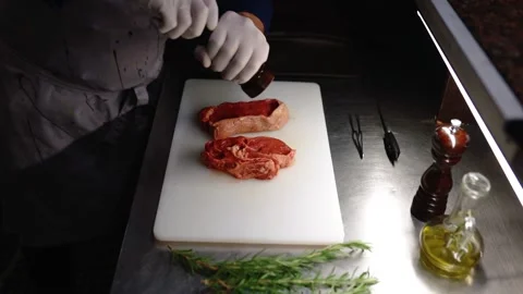 The cook salts an appetizing piece of meat. Stock Footage 145855398