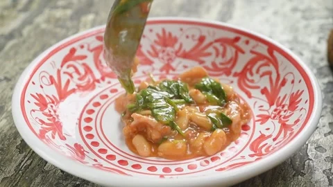 The cook serves bean stew with spinach on the plate. Stock Footage 240376513