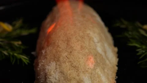 The cook sets fire to a salt cocoon on a black baking sheet. Flambé close-up Stock Footage 233356339