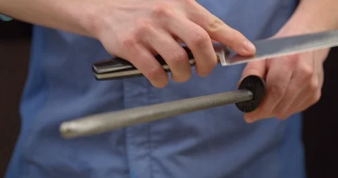 Cook sharpening a knife on a metal sharpener Stock Footage 113423085