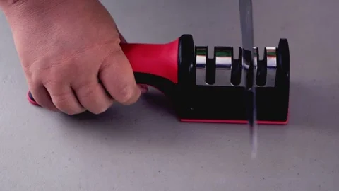 The cook sharpens a kitchen knife in a special knife sharpener on the table Stock Footage 264969389