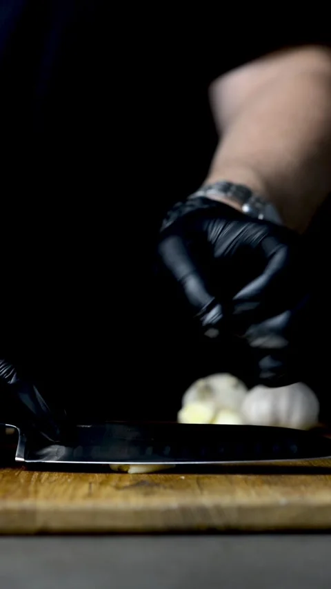 Cook slices garlic on a dark background Stock Footage 247199120