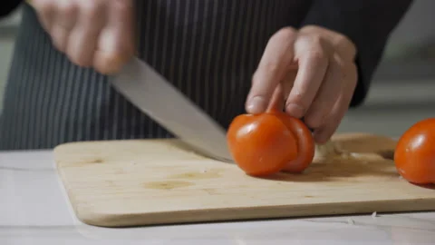 The cook slices tomato by sharp knife on the wooden board Stock Footage 102700016