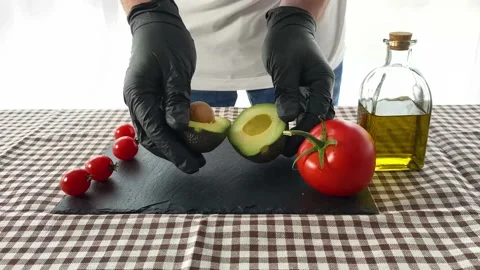Cook splitting an avocado in half on a table. Stock Footage 133078840