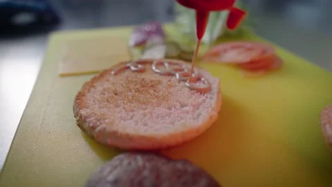 Cook spread the sauce on a burger bun using bottle. Cooking street food Stock Footage 175170028
