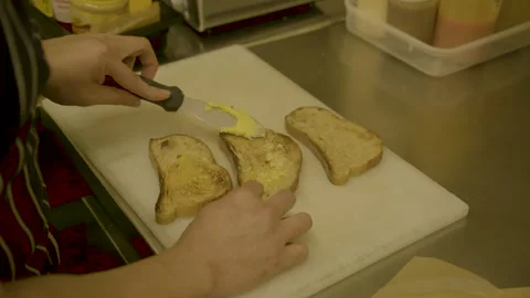 Cook Spreading Butter on Toasted Bread Slices in Sydney Cafe Kitchen Stock Footage 345654243