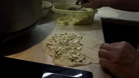 Cook spreading cheese and herb filling onto thin dough for making qutab fla.. Stock Footage 337669663