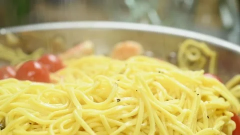 The cook sprinkles black pepper on the spaghetti in a frying pan. Stock Footage 168146751