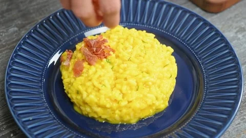 The cook sprinkles the pumpkin risotto witrh chopped prosciutto crudo. Stockbeeldmateriaal 207018568
