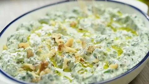The cook sprinkling walnuts over spinach and yogurt dip. Stock Footage 194922447