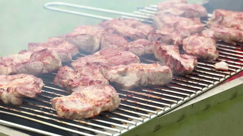 The cook is stabbing chunks of meat on the barbecue grill with a knife Stock Footage 136023608