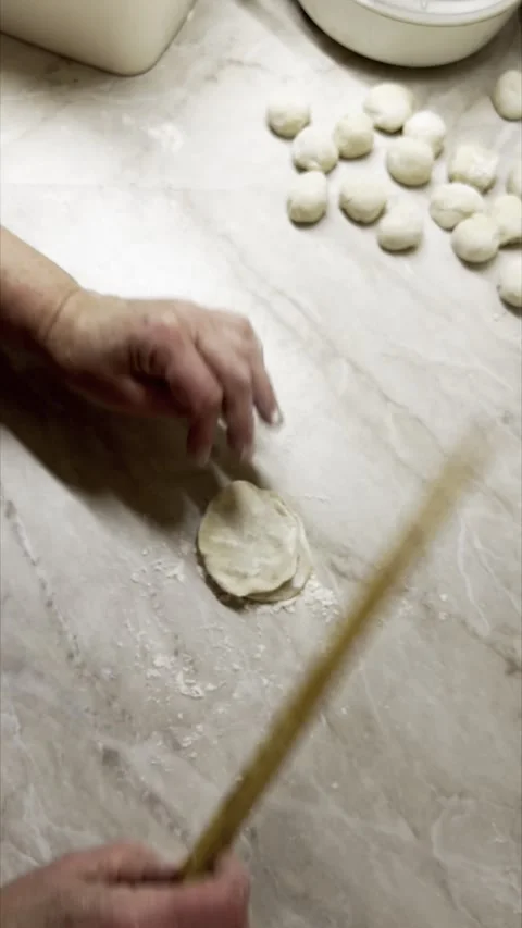 Cook stacking thin circles of rolled dough on a marble kitchen counter top Stock Footage 337669659