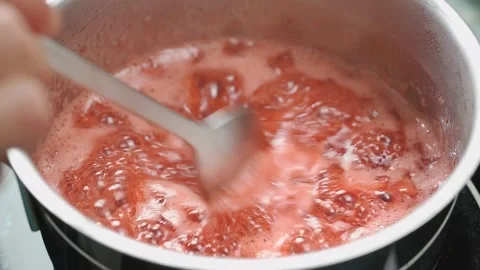 The cook stirs the strawberry jam while it boils in the saucepan. Stock Footage 209926484