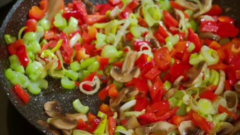 A cook stirs vegetables that are being fried in a pan with a wooden spatula. Stock Footage 309301865