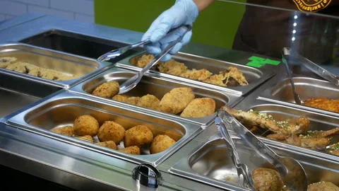 Cook takes a cutlet from dish and puts it in a bowl of porridge Stock Footage 98317170