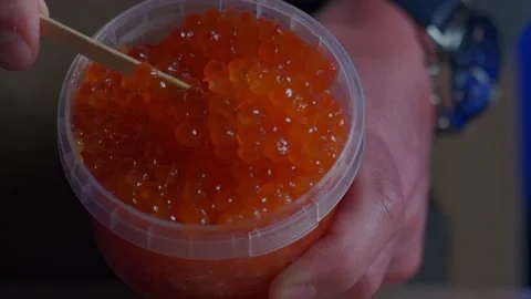 The cook takes red caviar out of the jar with a stick Stock Footage 181532042