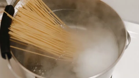 The cook throws pasta into boiling water. Cooks spaghetti for shrimp pasta. Video stock 204814092