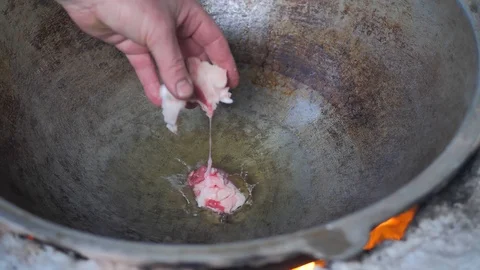 The cook throws pieces of meat into a hot iron pot 스톡 동영상 125523833