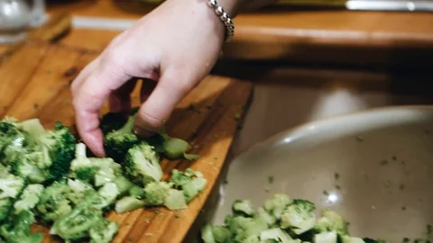 The cook throws the sliced broccoli into a plastic dish. Slow playback Stock Footage 123254804