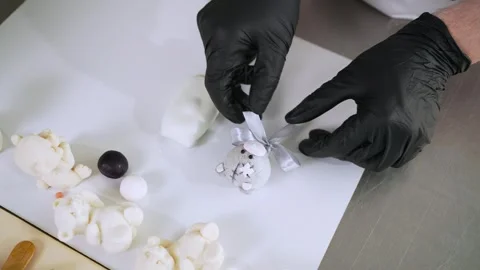 The cook ties a bow to the cupcake on a stick. He prepares sweet snacks for the Stock Footage 274064275