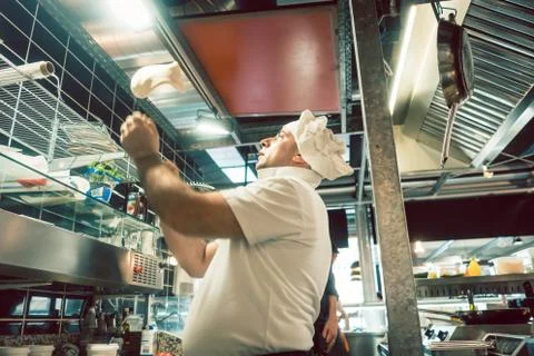 Cook tossing dough while preparing pizza in a modern Italian restaurant Stock Photos
