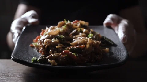 The cook in transparent gloves serves hot fresh wok in a black plate Stock Footage 125078159
