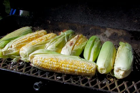 Cook turning corn on cob on barbecue grill Stock Footage